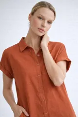 Camisa de corte holgado confeccionada en viscosa suave y liviana, con cuello clásico, cierre frontal de botones y mangas cortas con dobladillo. Cuenta con bolsillos laterales prácticos.