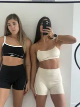 Conjunto deportivo compuesto por un top y un short de tiro alto en color beige con detalles en color tostado. El top presenta breteles finos y el short tiene un diseño ajustado con costuras laterales visibles.