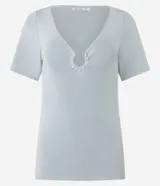 Blusa de manga corta confeccionada en tejido de viscosa texturizado, con escote en V profundo que presenta un detalle de aro metálico central.