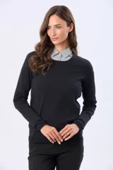 Buzo tejido en hilo de algodón color beige, con cuello redondo y manga larga. Presenta un corte clásico y un pequeño detalle metálico en la parte inferior izquierda.