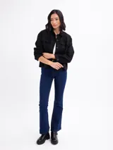 Chaqueta de gamuza sintética color negro, con cuello camisero, bolsillos frontales con solapa, cierre de botones y mangas largas.