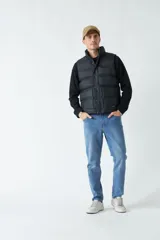 Chaleco color camel de nylon con cierre frontal con broches a presión, cuello alto y bolsillos laterales.