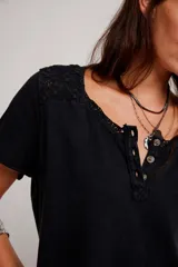 Remera henley de algodón liviano y jaspeado, de calce relajado, color blanco off-white, con mangas cortas, botonadura al cuello, aplicaciones de encaje y ruedo enrollado.