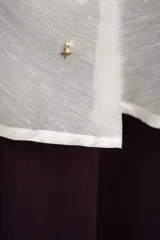 Top de tirantes blancos con diseño fluido y volado superpuesto en el pecho.