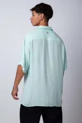 Camisa de manga corta con cuello cubano, confeccionada en fibrana premium. Presenta un corte oversize y cierre frontal con botones al tono.