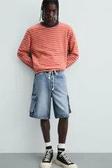 Bermuda de denim de algodón, color celeste lavado, de corte relajado (relaxed fit). Presenta cinco bolsillos, incluyendo bolsillos cargo plastrón con solapa en las perneras.