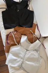 Top de cuero negro ovino con detalles artesanales en pasamanería, con breteles trenzados dorados y lazos de ajuste frontales.