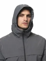 Campera rompevientos de nylon color gris, con capucha ajustable, cierre frontal completo, bolsillos laterales con cierre, puños elásticos y ruedo ajustable.