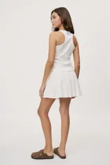 Falda corta blanca con diseño de volados escalonados y cintura elastizada, de silueta fluida y liviana.