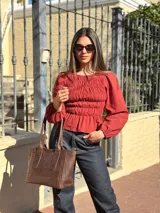 Blusa bordó con diseño fruncido mediante elásticos en el cuerpo y mangas largas abullonadas con puños elásticos.