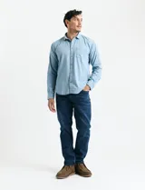 Camisa de denim de algodón con cuello clásico, cierre frontal con botones, bolsillo superior de parche y mangas largas con puños abotonados.