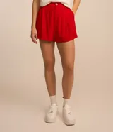 Short holgado de viscosa texturizada color blanco, con cintura de sastrería en la parte delantera y elástico en la trasera, bolsillos laterales y cierre con botón y cremallera.