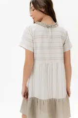 Vestido corto de algodón a rayas horizontales color beige, con cuello redondo negro y falda negra de lino.