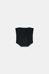 Corsé de escote strapless con detalle de drapeado en el pecho y varillas frontales visibles. Presenta un bajo asimétrico y cierre en la espalda.
