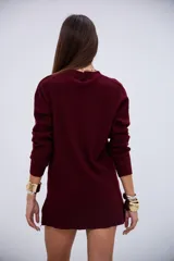 Sweater de punto acanalado en color bordó, con cuello en V y mangas largas. Presenta un diseño de corte recto con aberturas laterales en el ruedo.