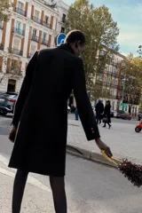 Abrigo de paño color beige con cuello solapa, manga larga con hombreras y cierre frontal con botones. Presenta bolsillos delanteros de doble vivo y abertura en la espalda.