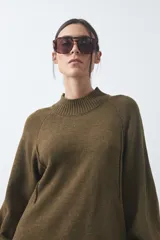 Vestido corto de punto en color beige, con cuello alto acanalado, mangas largas con puños ajustados y diseño holgado.