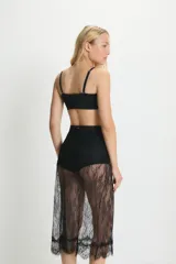 Pollera midi de encaje negro translúcido con terminación de puntilla en el ruedo. Presenta un diseño de tiro alto con cierre invisible lateral.