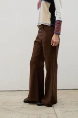 Pantalón de denim tiro alto con corte oxford y tajos laterales en el ruedo. Presenta cierre frontal con botones a la vista y costuras verticales decorativas.