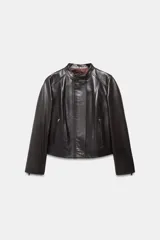 Chaqueta de cuero de corte entallado con cuello subido, cierre frontal con cremallera y botones ocultos bajo solapa. Presenta bolsillos delanteros con cierre y mangas largas terminadas en cremalleras metálicas.