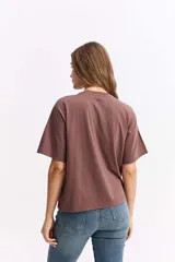 Remera de algodón color marrón con estampa gráfica frontal en tonos oscuros y texto.