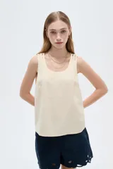 Musculosa de viscosa color beige claro, holgada, con cuello redondo y tirantes anchos formados por múltiples tiritas trenzadas.