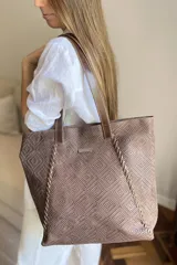 Bolso grande tipo tote de cuero con textura trenzada, color marrón. Cuenta con doble asa de hombro, cierre principal, bolsillo interior con cierre, compartimento para celular y bolsillo trasero con cierre.