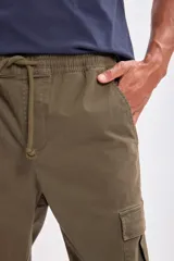 Pantalón cargo estilo jogger color verde militar, con cintura elástica ajustable con cordón y puños elásticos en los tobillos. Presenta bolsillos cargo en los laterales de las piernas.