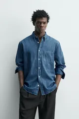 Camisa regular fit de denim de algodón azul, con cuello solapa, manga larga con puños abotonados, un bolsillo de parche en el pecho y cierre frontal de botonadura.
