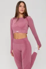 Conjunto deportivo de tres piezas en color rosa viejo, compuesto por un top de bretel ancho, un top de manga larga y una calza chupín. Las prendas presentan un diseño sin costuras con detalles de tejido texturizado y el logo de la marca estampado en blanco.