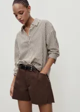 Short de algodón estilo denim, color marrón, con tiro medio, pinzas delanteras, cuatro bolsillos y bajo deshilachado.