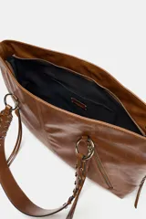 Bolso shopper de hombro color negro, con detalle de flecos y trenzados en el cuerpo. Tiene doble cremallera metálica, asa doble con detalles metálicos y trenzados, y un bolsillo interior. El cierre es mediante cremallera metálica.