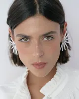 Caravanas de diseño tipo medio sol, compuestas por varillas de resina blanca dispuestas en abanico y un centro circular decorado con strass. Presentan un estilo moderno y liviano.