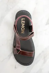 Sandalias de cuero color marrón con textura tipo cocodrilo, plataforma plana y tira ajustable con hebilla.