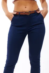 Pantalón azul marino de corte skinny, con bolsillos laterales y traseros. Se ajusta a la cintura con cinturón de cuero marrón.