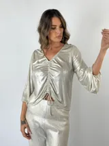 Blusa metalizada color gris con escote en V, mangas largas abullonadas y fruncido central con cordón ajustable.