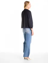 Blusa de gasa con plisado soleil, cuello a la base fruncido con escote en V regulable mediante lazos, y mangas largas abullonadas con puños sastreros.