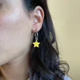 Par de aros plateados con dije colgante de estrella color amarillo.