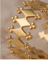 Anillo de acero con baño de oro, diseño calado con formas geométricas de rombos y detalles de esferas pequeñas.
