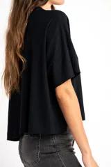 Remera de corte oversize, confeccionada en tejido de viscosa con textura acanalada, de color negro, con mangas cortas y cuello redondo.
