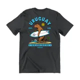 Remera de algodón color gris oscuro con estampa gráfica en la espalda que presenta un carpincho surfista, el sol de mayo y la leyenda Uruguay.