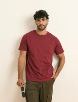 Remera básica de algodón color beige, de manga corta, con cuello redondo y un pequeño detalle bordado en el pecho.