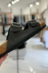 Sandalia marrón con diseño de dos tiras ajustables con hebillas metálicas y plantilla anatómica.