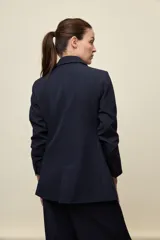 Blazer negro de líneas clásicas y silueta sastrera, con solapas y estructura definida.