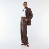 Pantalón marrón de corte ancho y talle alto, con estampado a cuadros y pinzas en la parte delantera.