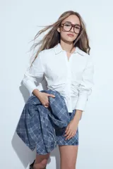Camisa blanca de manga larga con cuello clásico y cierre frontal de botones. Presenta un diseño entallado con frunces decorativos en la parte central delantera.