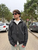Campera con capucha y cierre frontal, de corte oversize y acabado acid wash en color gris oscuro. Presenta costuras curvas decorativas en el frente y puños acanalados.