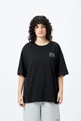 Remera negra de corte holgado con mangas cortas amplias y cuello redondo. Estampado frontal con la palabra 'UNLEARN' repetida tres veces en color gris claro.