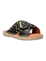 Sandalia tipo ojota con base de yute, tiras cruzadas de cuero negro con tachas doradas y hebilla metálica decorativa.