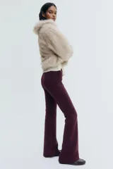 Pantalón de tiro alto confeccionado en punto roma, con diseño ajustado en la parte superior y piernas acampanadas. Presenta bolsillos insertados decorativos en la parte frontal.
